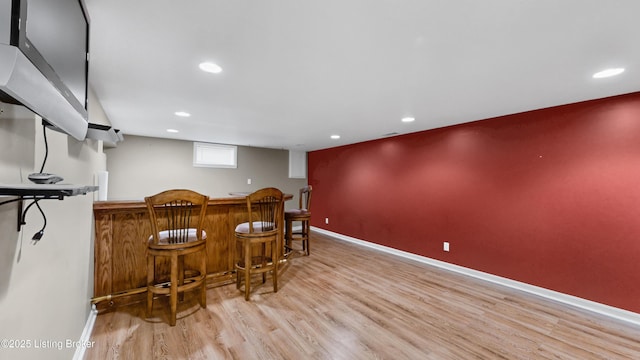 bar with recessed lighting, baseboards, a bar, and wood finished floors