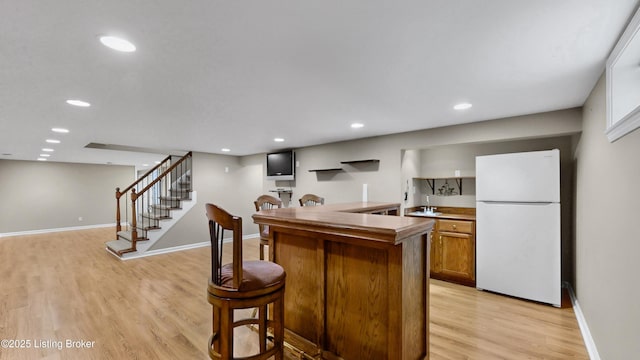 kitchen featuring brown cabinetry, baseboards, light wood finished floors, recessed lighting, and freestanding refrigerator