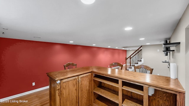 bar with baseboards, stairway, recessed lighting, wood finished floors, and a bar