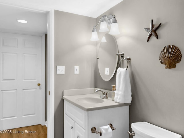 half bathroom with toilet, vanity, and wood finished floors