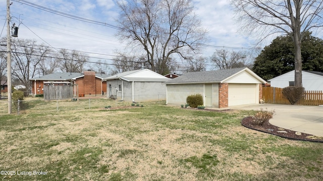 view of yard featuring a detached garage, an outbuilding, and fence