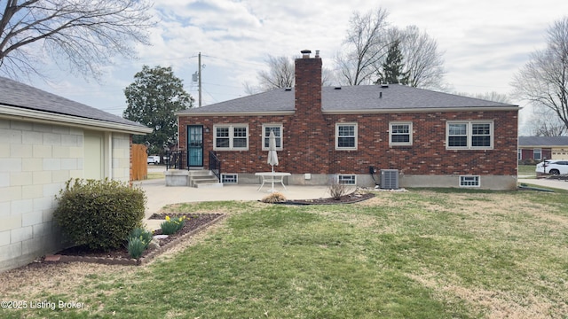 back of property with a patio, roof with shingles, a chimney, a lawn, and brick siding