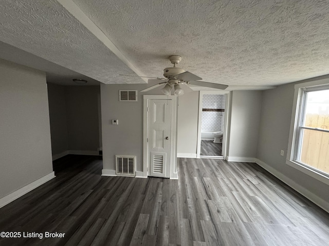 empty room featuring dark wood finished floors, visible vents, and baseboards