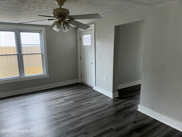 empty room with baseboards, a textured ceiling, and wood finished floors