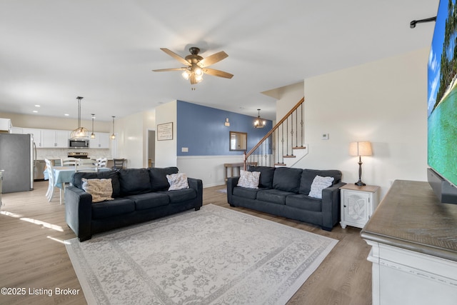 living area featuring stairs, light wood-style floors, and ceiling fan