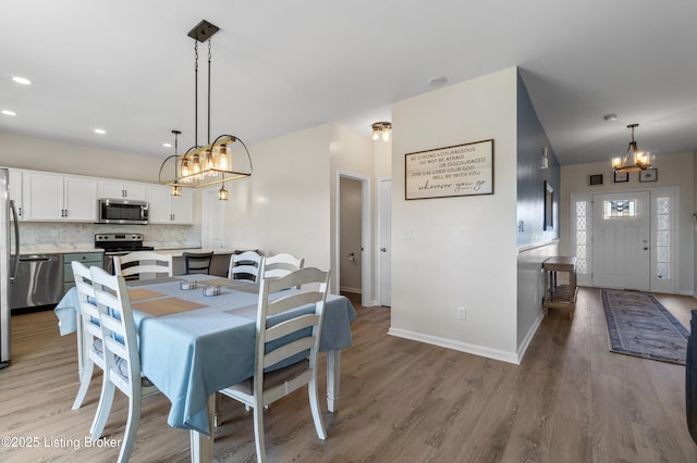 dining room featuring light wood finished floors, recessed lighting, baseboards, and an inviting chandelier