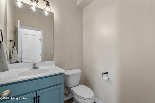 half bath featuring toilet, vanity, and baseboards