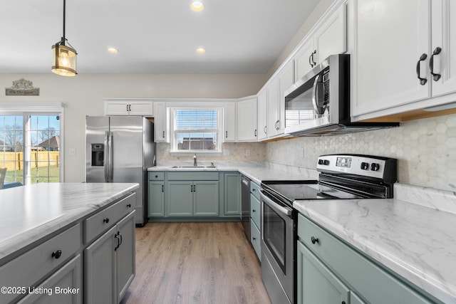 kitchen with tasteful backsplash, light wood finished floors, appliances with stainless steel finishes, and a sink