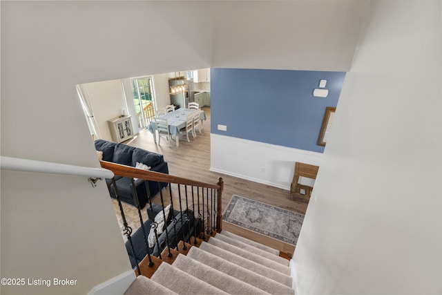 stairs featuring a chandelier, a high ceiling, baseboards, and wood finished floors