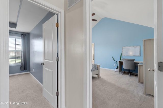 hallway featuring visible vents, baseboards, lofted ceiling, and carpet