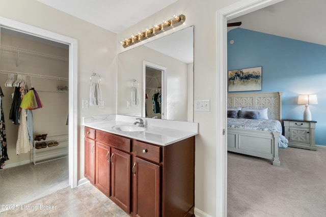 bathroom featuring vanity, lofted ceiling, and a walk in closet