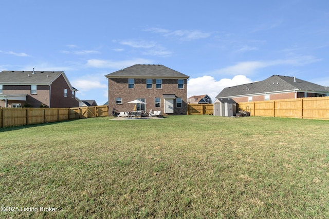 rear view of house featuring an outbuilding, a yard, a fenced backyard, a storage shed, and a patio area