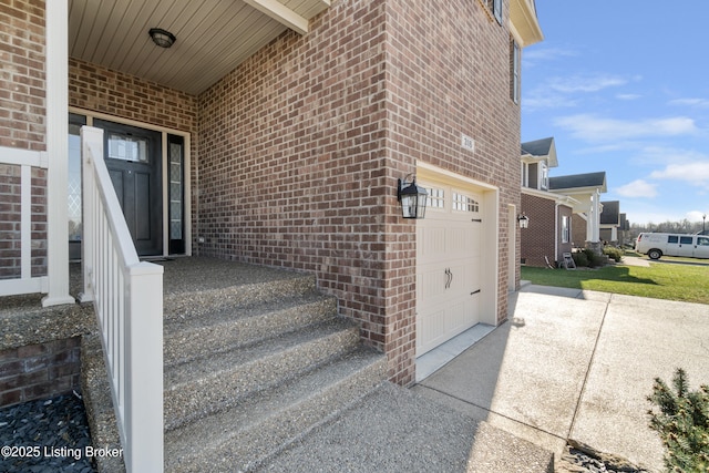 property entrance with brick siding, an attached garage, and concrete driveway