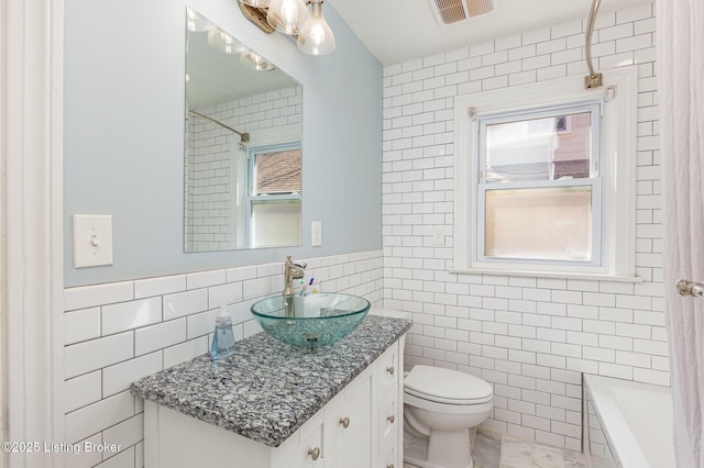 full bathroom with vanity, visible vents, walk in shower, tile walls, and toilet