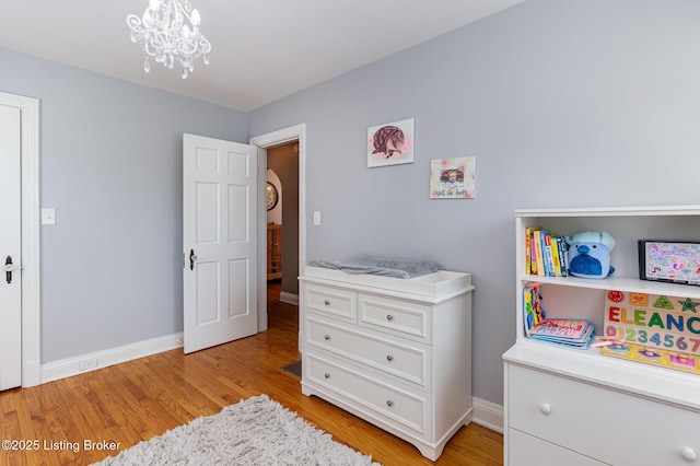 bedroom with a chandelier, baseboards, and light wood-style flooring