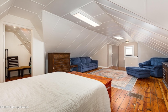 bedroom featuring hardwood / wood-style flooring, visible vents, and vaulted ceiling