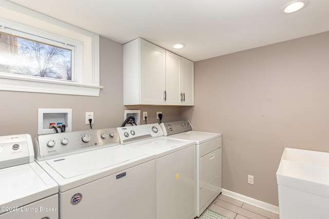 clothes washing area with a sink, baseboards, cabinet space, and washing machine and dryer