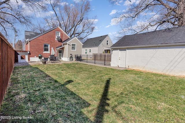 rear view of property featuring brick siding, a patio area, a lawn, and a fenced backyard