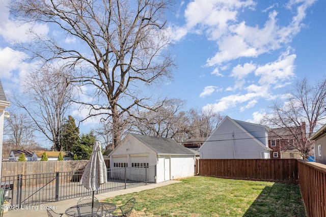 view of yard with a detached garage, an outbuilding, a fenced backyard, and a patio area