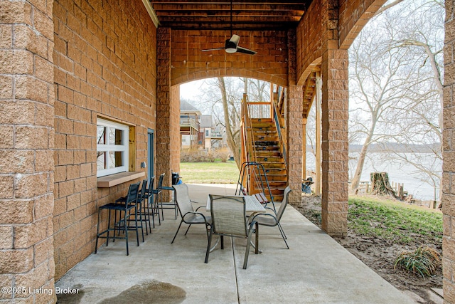 view of patio / terrace with ceiling fan and stairs