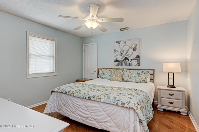 bedroom featuring visible vents, wood finished floors, baseboards, and a textured ceiling