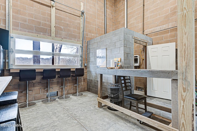 misc room with heating unit, concrete floors, and a towering ceiling