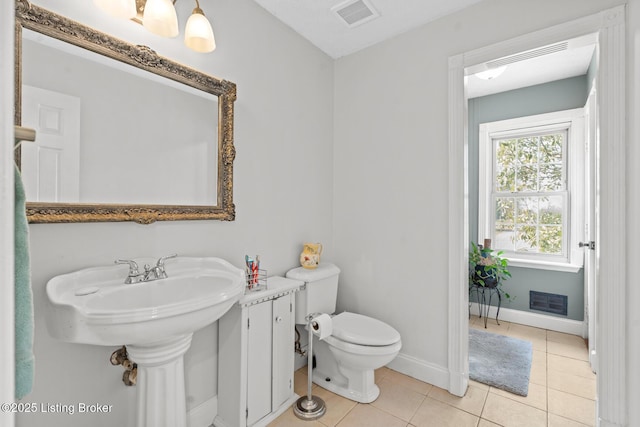 half bath featuring visible vents, baseboards, toilet, and tile patterned flooring