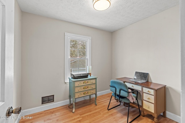 home office featuring visible vents, baseboards, a textured ceiling, and wood finished floors