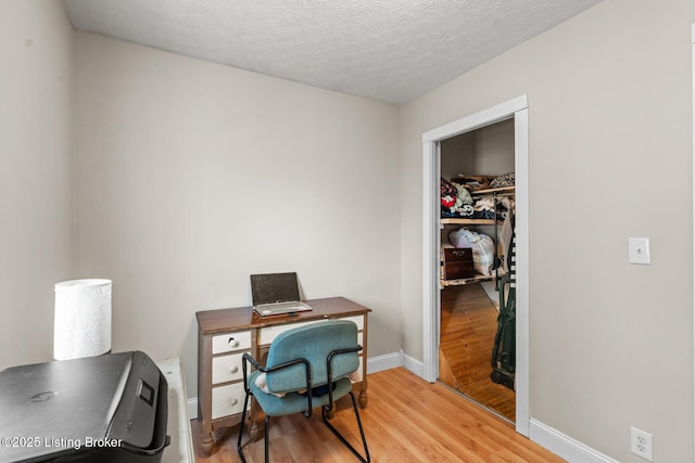 office featuring baseboards, light wood-style floors, and a textured ceiling