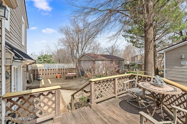 wooden terrace featuring an outbuilding and fence