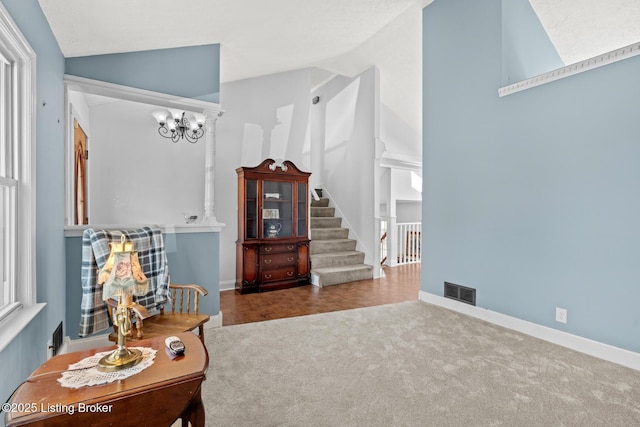 sitting room featuring visible vents, stairway, lofted ceiling, carpet flooring, and a notable chandelier