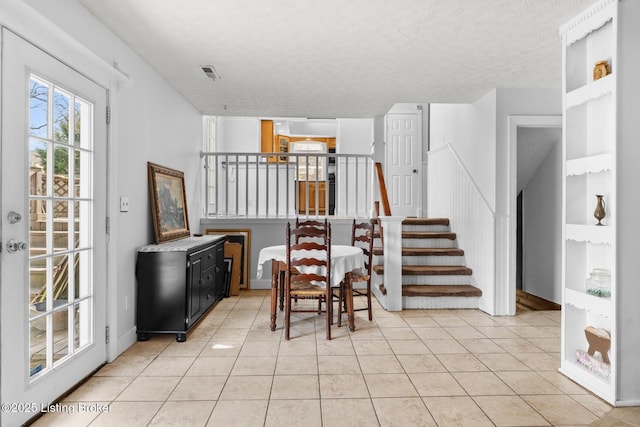 dining room with stairs, light tile patterned floors, visible vents, and a textured ceiling