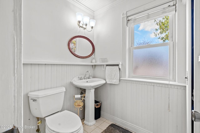 bathroom featuring tile patterned flooring, toilet, ornamental molding, and wainscoting