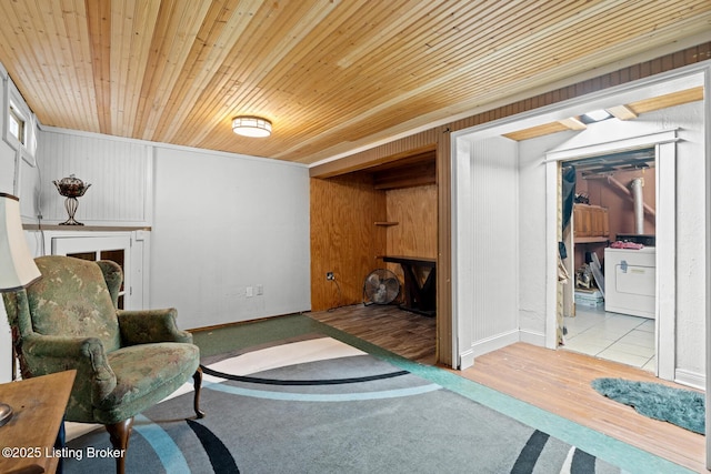 living area with wood finished floors, baseboards, washer / dryer, a fireplace, and wooden ceiling