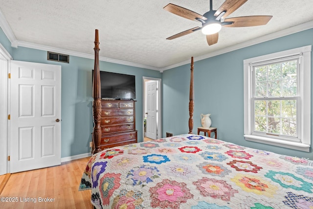 bedroom featuring crown molding, light wood-style flooring, visible vents, and a textured ceiling