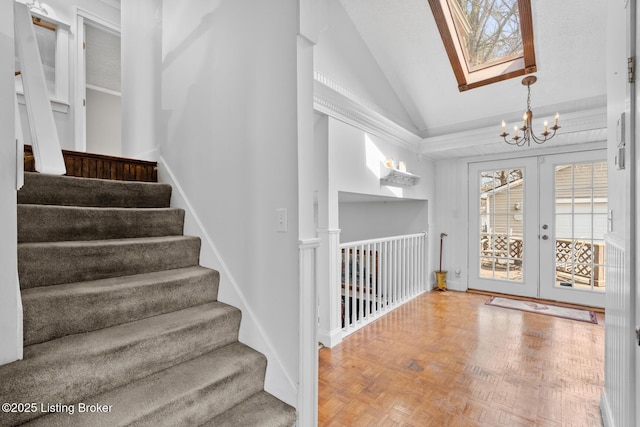 stairs featuring french doors, vaulted ceiling with skylight, and an inviting chandelier