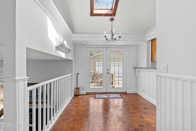 interior space with french doors, vaulted ceiling with skylight, and a notable chandelier