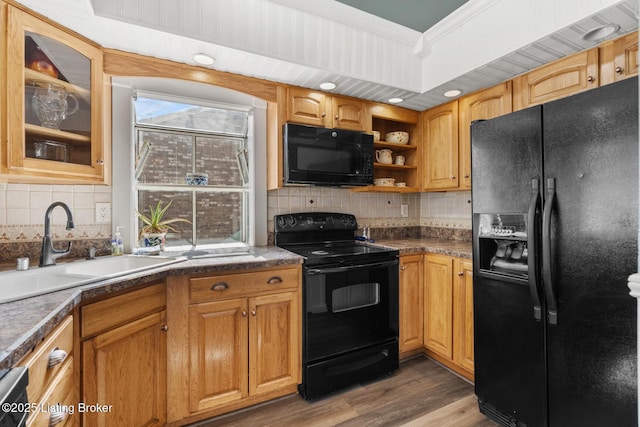 kitchen with wood finished floors, black appliances, decorative backsplash, and a sink