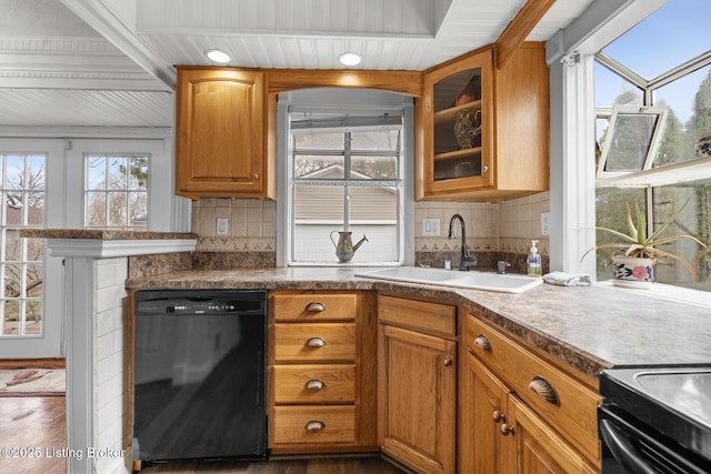 kitchen featuring a sink, backsplash, wood finished floors, glass insert cabinets, and dishwasher