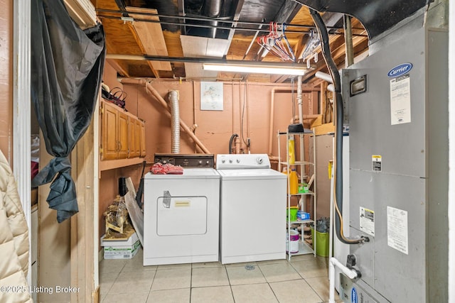 washroom featuring heating unit, laundry area, light tile patterned floors, and separate washer and dryer