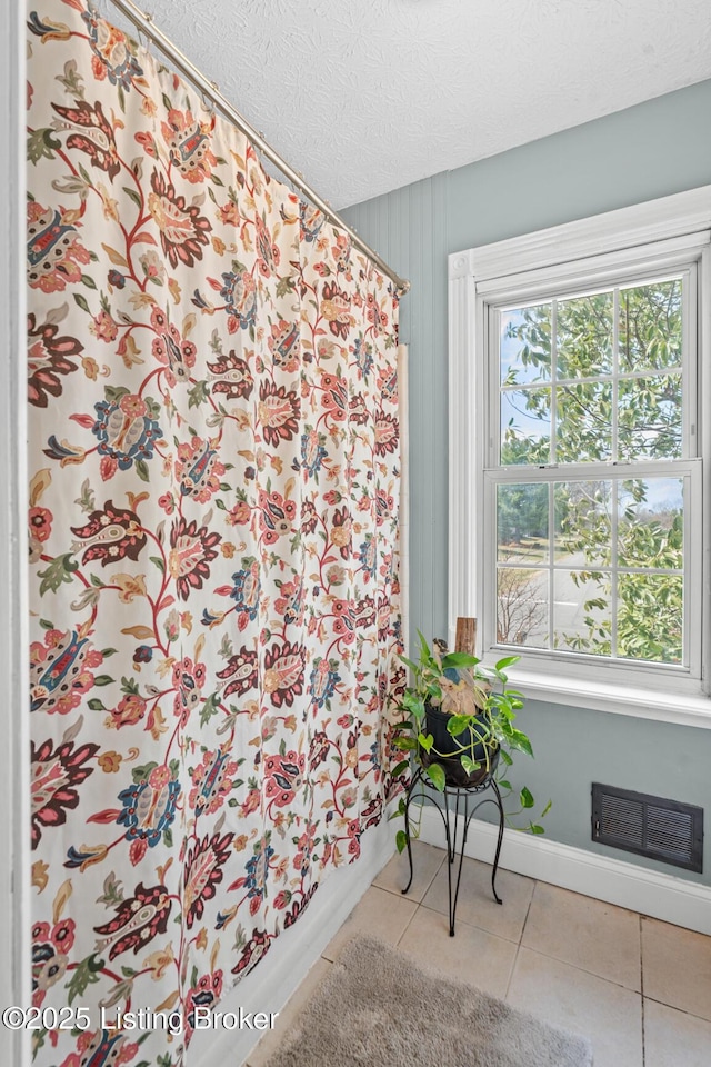 full bath with tile patterned flooring, visible vents, baseboards, a shower with curtain, and a textured ceiling