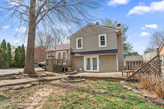 rear view of property featuring a chimney, french doors, a wooden deck, and fence