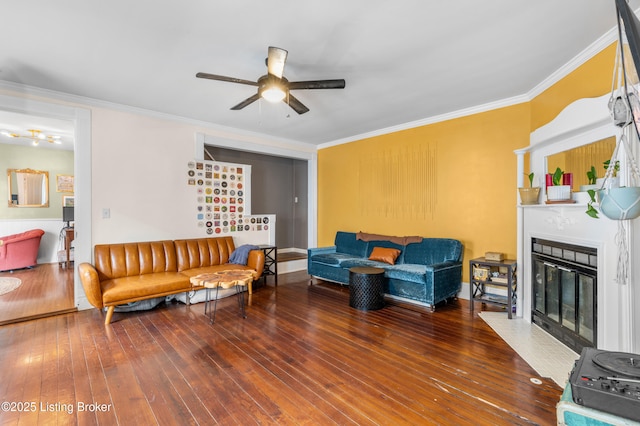 living room with hardwood / wood-style flooring, a fireplace with flush hearth, a ceiling fan, and ornamental molding