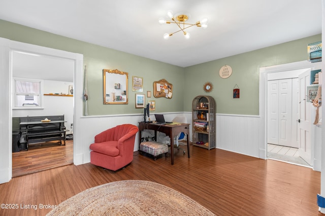 sitting room featuring wood finished floors, a wainscoted wall, and a chandelier