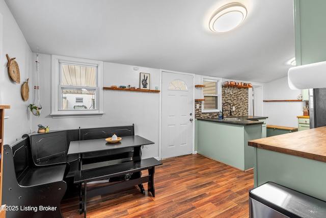 kitchen with a sink, wood counters, tasteful backsplash, dark wood finished floors, and green cabinets