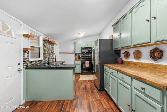 kitchen with wood counters, black appliances, green cabinets, and a sink