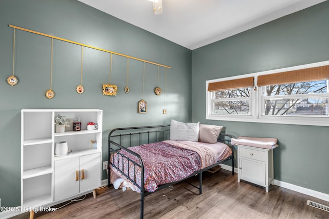 bedroom featuring visible vents, baseboards, and wood finished floors