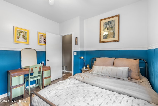 bedroom with wood finished floors and a wainscoted wall