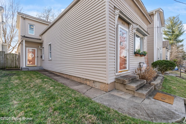 view of property exterior featuring entry steps, a yard, and fence