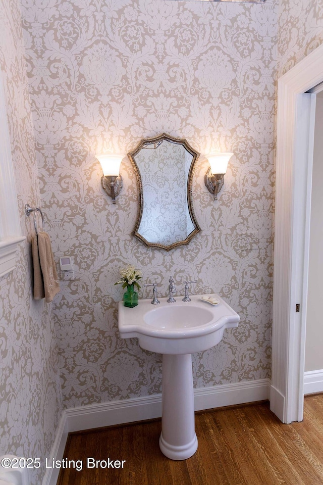 bathroom with wallpapered walls, baseboards, and wood finished floors